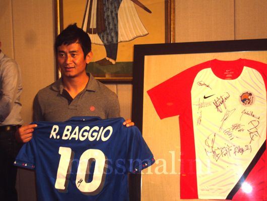 Bhaichung holds up a jersey autographed by Roberto Baggio which is for auction