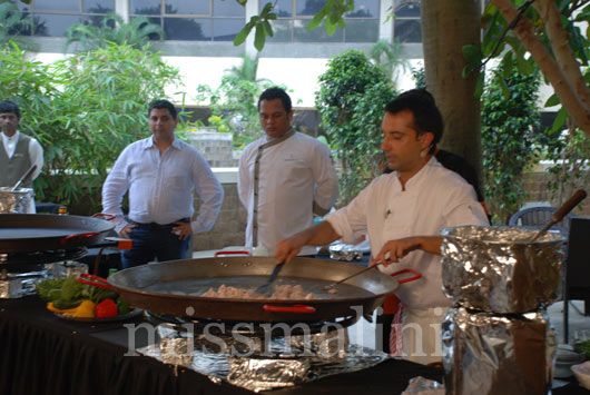 Farrokh watches as Chef Hidalgo cooks the chicken in the Paella