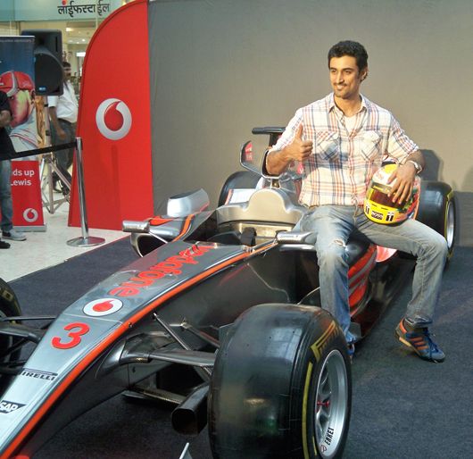 Kunal Kapoor poses with a replica of a Formula 1 car