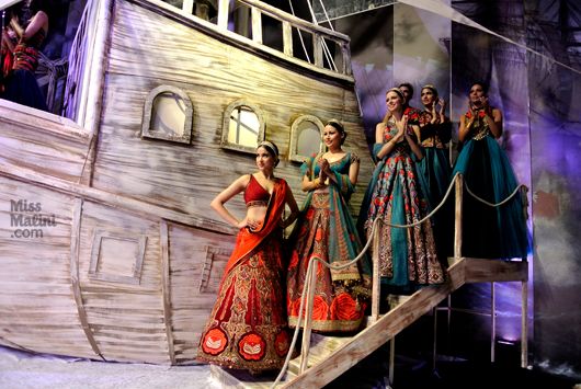 Models stand against the huge ship on the catwalk