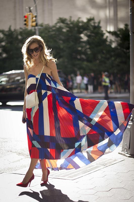 Fashion week streetstyle beauty pulls off a bold abstract print sweetheart dress with fierce red pumps.