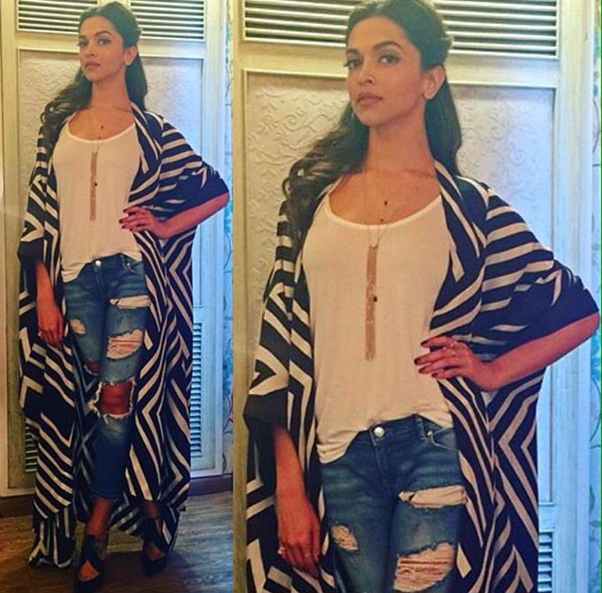 Deepika Padukone in a pair ripped jeans, a white tee and striped cape cover-up.