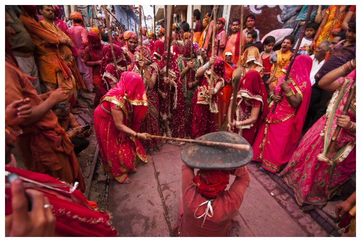 Women beat up men with long sticks as a ritual in the Lathmar Holi celebrations in Nandgaon, India by CRS PHOTO | www.shutterstock.com