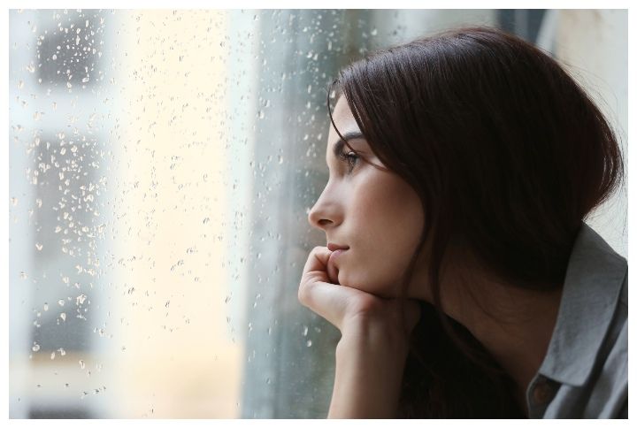 Depressed young woman near window at home by African Studio | (Source: Shutterstock)
