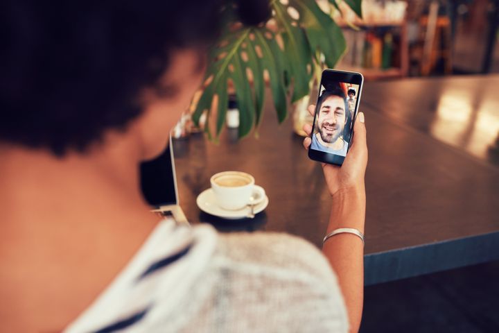 Young man and woman talking to each other through a video call on a smartphone. Young woman having a videochat with man on mobile phone. Woman sitting at a coffee shop By Jacob Lund | www.shutterstock.com