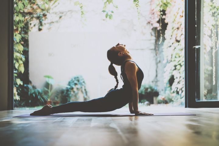 Portrait of gorgeous young woman practicing yoga indoor. Beautiful girl practice cobra asana in class. Calmness and relax, female happiness. Horizontal, blurred background By SFIO CRACHO | www.shutterstock.com