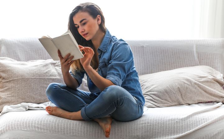 White cozy bed and a beautiful girl, reading a book, concepts of home and comfort, place for text By PV productions | www.shutterstock.com