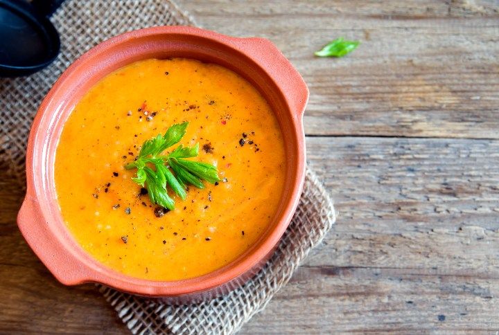 Vegetable tomato and carrot soup in ceramic pot over rustic wooden background with copy space By Oksana Mizina | www.shutterstock.com