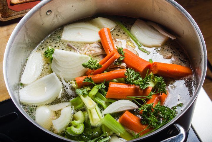 A large stock pot on a stove with vegetables cut for making soup Z By Zigzag Mountain Art | www.shutterstock.com