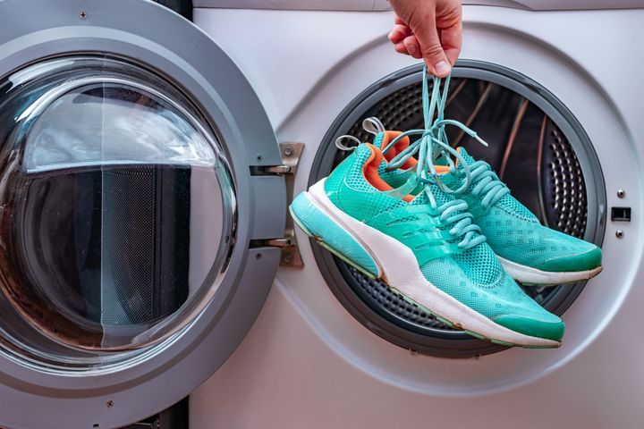 Cleaning dirty sports shoes in a washing machine at home. By goffkein.pro | www.shutterstock.com