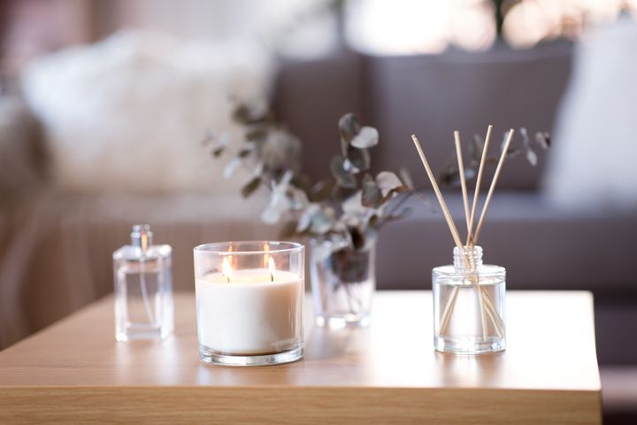Scented candles and aromatherapy concept: aroma reed diffuser, burning candle, branches of eucalyptus populous and perfume on table at home. By Syda Productions | www.shutterstock.com