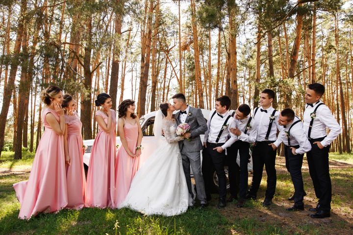 Bridesmaids in pink dresses and groomsmen with bow ties and suspenders By Wedding and lifestyle | www.shutterstock.com