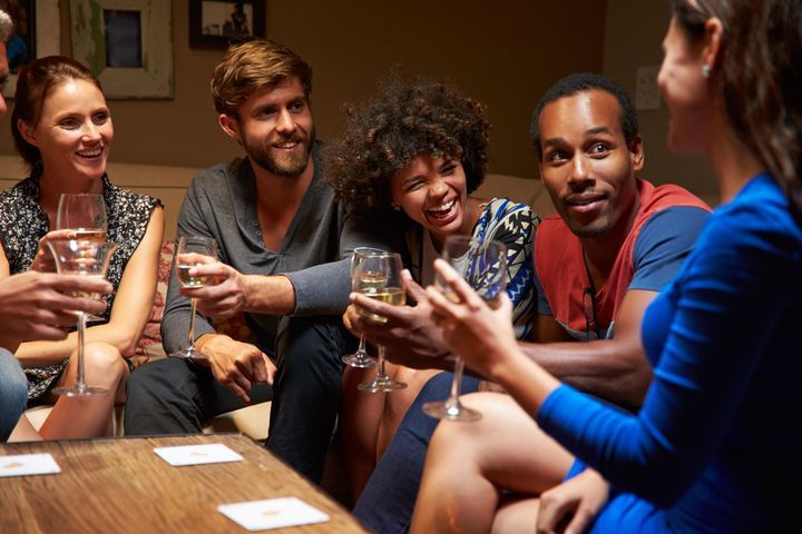 Group of friends sitting around a table at house party. By Monkey Business Images | www.shutterstock.com