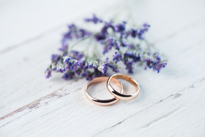 Gold wedding ring with small blue flowers on wooden tabletop By LightField Studios | www.shutterstock.com