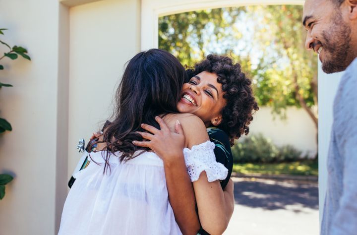 Couple welcoming friend for house party. By Jacob Lund | www.shutterstock.com