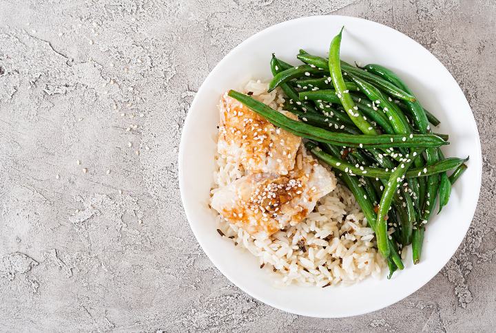 Fish fillet served with rice, soy sauce and green beans in white plate By Timolina | www.shutterstock.com