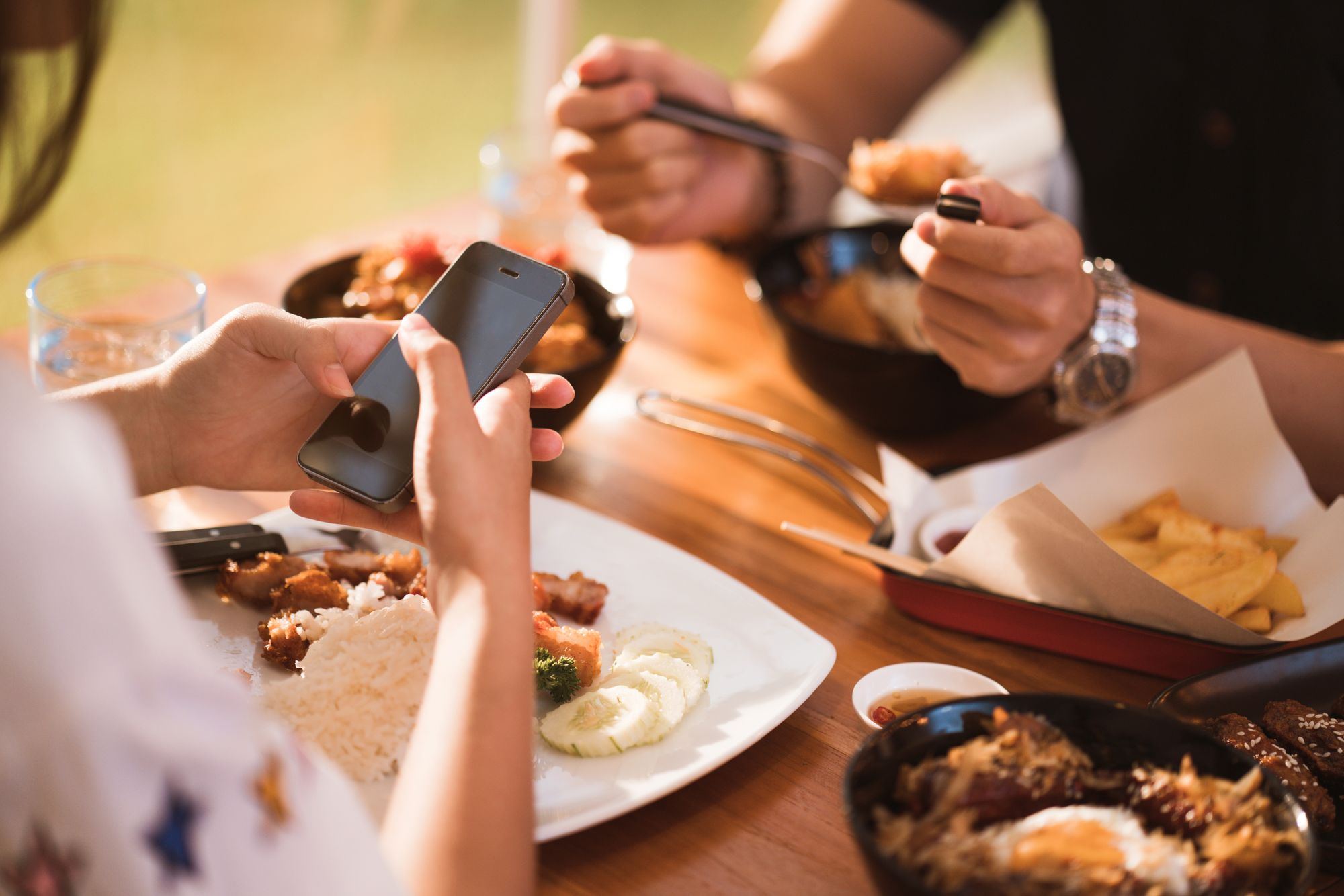 Using your phone while eating by TORWAISTUDIO | www.shutterstock.com